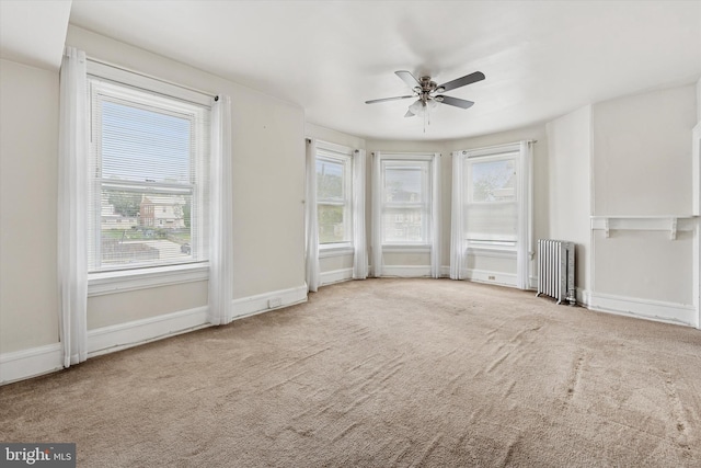 unfurnished living room featuring radiator, carpet flooring, ceiling fan, and baseboards