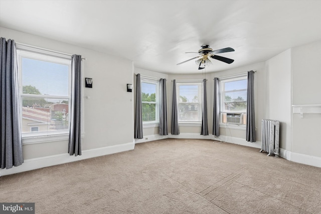 unfurnished living room featuring radiator, ceiling fan, light carpet, and cooling unit
