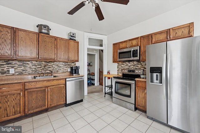 kitchen featuring stainless steel appliances, a sink, a ceiling fan, and tasteful backsplash