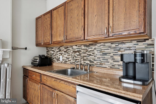 kitchen with a sink, backsplash, dishwasher, brown cabinetry, and light countertops