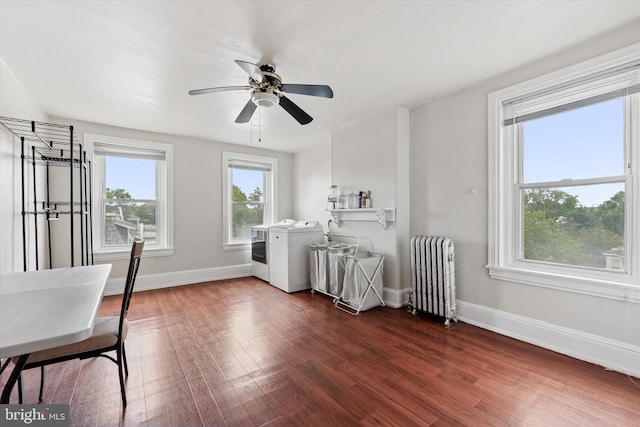 interior space featuring radiator heating unit, washer and dryer, dark wood-style floors, baseboards, and ceiling fan