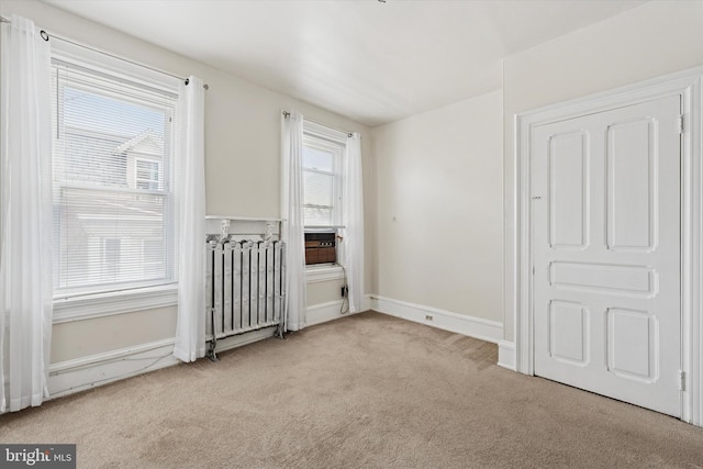 unfurnished bedroom with carpet floors, radiator, and baseboards