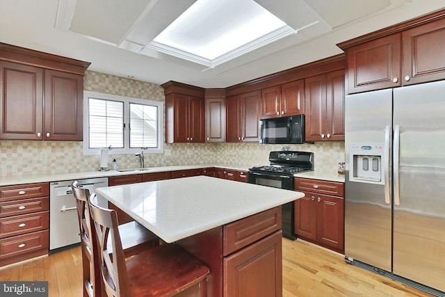 4501 Highland Green Ct, Alexandria, VA 22312 - kitchen featuring black appliances, a sink, light wood-style floors, a breakfast bar area, and light countertops