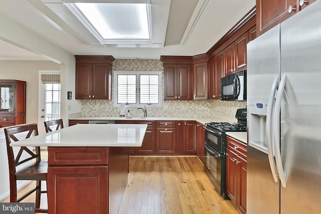 4501 Highland Green Ct, Alexandria, VA 22312 - kitchen featuring black appliances, a breakfast bar, light wood-type flooring, light countertops, and a sink