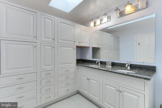 4501 Highland Green Ct, Alexandria, VA 22312 - kitchen with a sink, a skylight, light tile patterned floors, and dark stone countertops