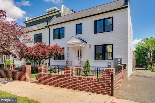 townhome / multi-family property with brick siding and a fenced front yard