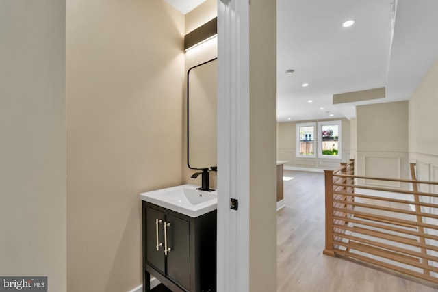 bathroom featuring wood finished floors, recessed lighting, vanity, and a wainscoted wall