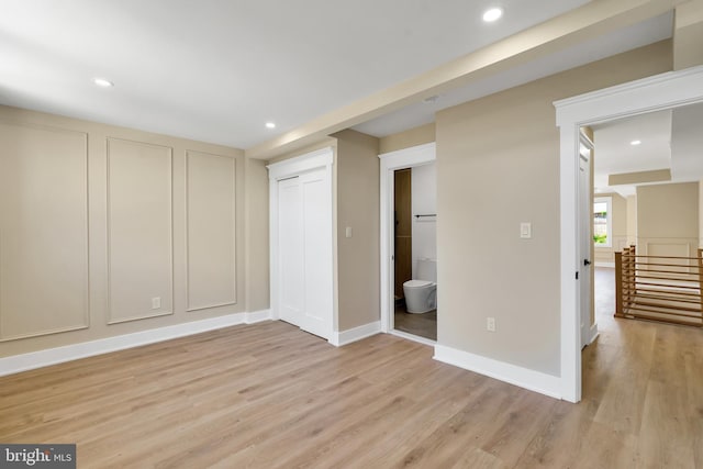 unfurnished bedroom with light wood finished floors, recessed lighting, baseboards, and ensuite bathroom