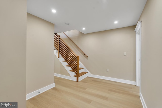 staircase featuring wood finished floors, baseboards, and recessed lighting