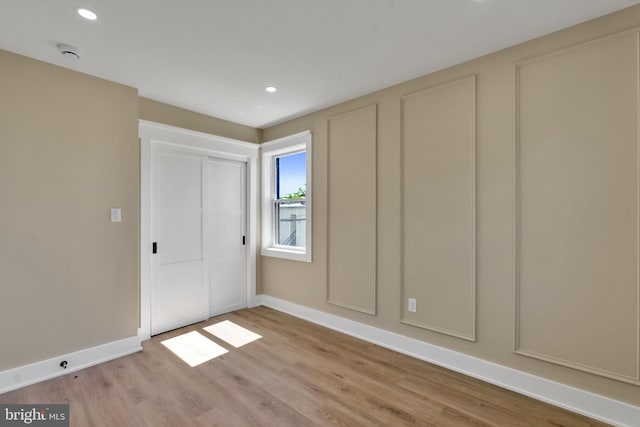 unfurnished bedroom featuring light wood-type flooring, baseboards, recessed lighting, and a closet