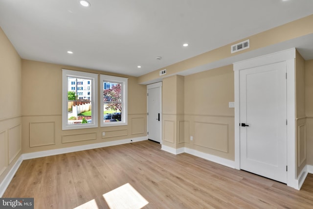 unfurnished bedroom featuring a decorative wall, light wood-type flooring, wainscoting, and recessed lighting