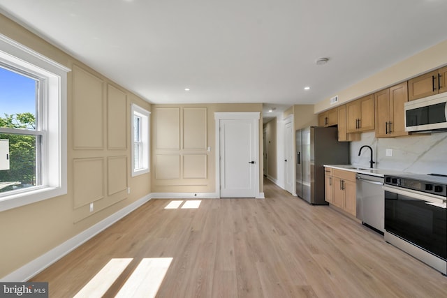 kitchen with appliances with stainless steel finishes, baseboards, light wood-style flooring, light countertops, and tasteful backsplash