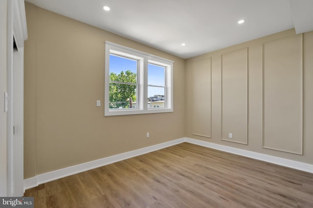 spare room featuring wood finished floors, baseboards, and recessed lighting