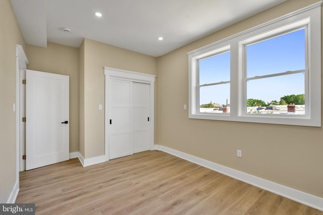 unfurnished bedroom with baseboards, light wood finished floors, recessed lighting, and a closet