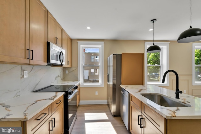 kitchen featuring stainless steel appliances, a sink, light wood-style floors, tasteful backsplash, and baseboards