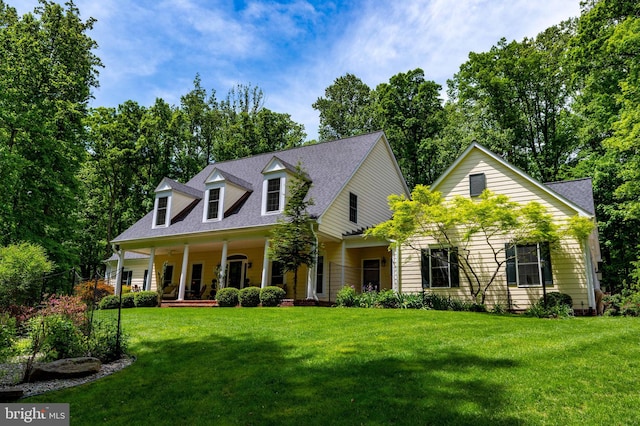 cape cod-style house with a front lawn, covered porch, and a shingled roof