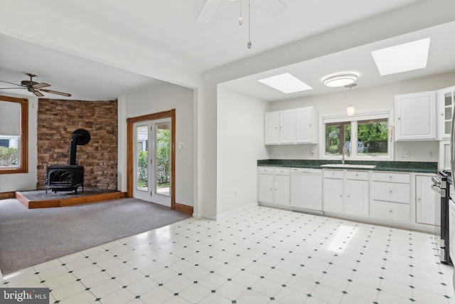 3113 White Ave, Baltimore, MD 21214 - kitchen featuring white dishwasher, a wood stove, a skylight, dark countertops, and ceiling fan