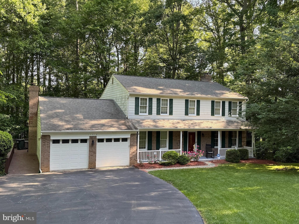 11316 Robert Carter Rd, Fairfax Station, VA 22039 - colonial house with a chimney, covered porch, driveway, an attached garage, and a front lawn