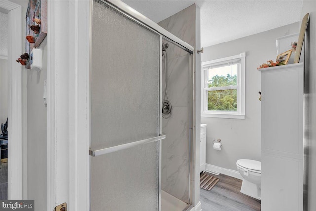 full bath featuring toilet, a shower stall, baseboards, and wood finished floors