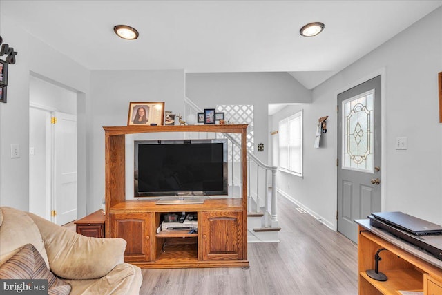 living room featuring light wood-type flooring, baseboards, and lofted ceiling