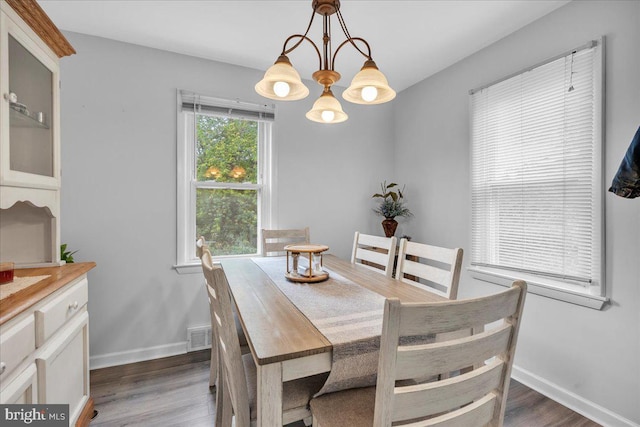 dining room with dark wood-type flooring, baseboards, and a chandelier
