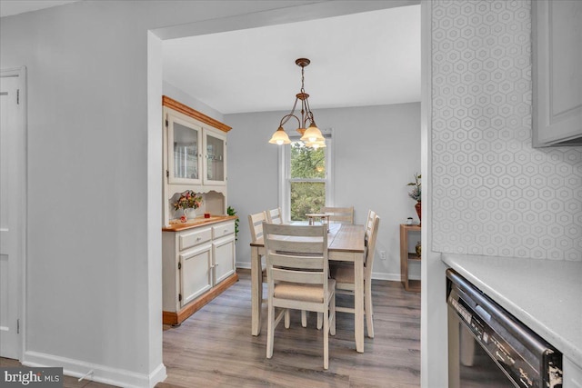 dining area featuring light wood-type flooring, a chandelier, and baseboards