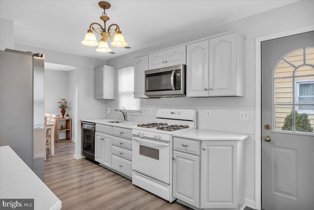 kitchen with stainless steel appliances, a sink, a chandelier, light countertops, and light wood-style flooring