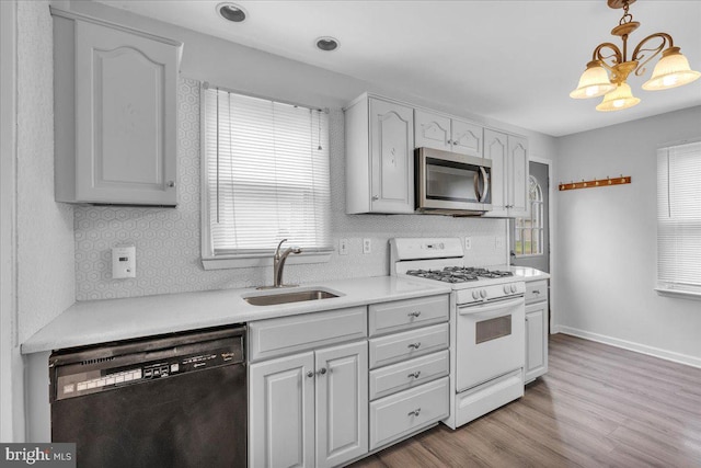 kitchen with stainless steel microwave, white gas range, black dishwasher, a sink, and healthy amount of natural light