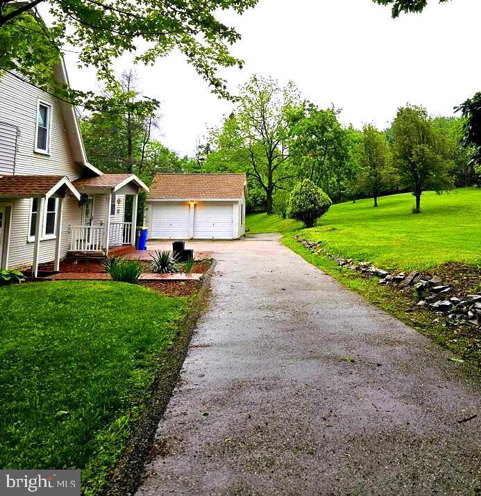 view of side of property featuring a porch, a lawn, and a garage