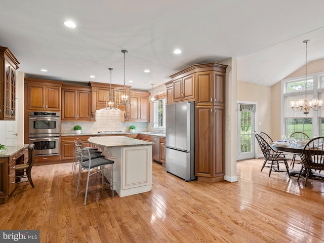 kitchen with stainless steel appliances, a chandelier, brown cabinets, a kitchen breakfast bar, and recessed lighting