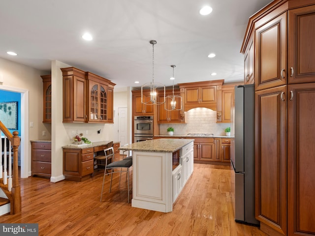 kitchen featuring appliances with stainless steel finishes, a kitchen breakfast bar, brown cabinetry, glass insert cabinets, and recessed lighting