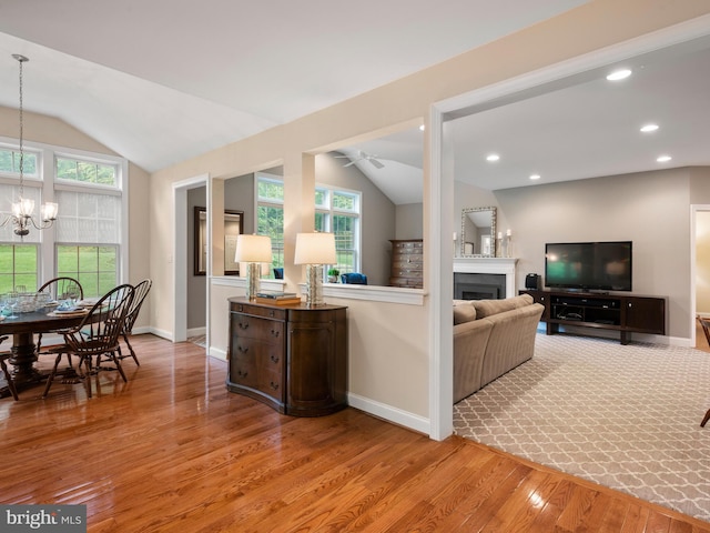 living room featuring vaulted ceiling, wood finished floors, ceiling fan, baseboards, and a fireplace