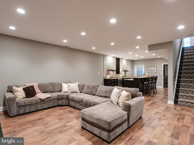 living room with wet bar, recessed lighting, light wood-style floors, stairway, and baseboards