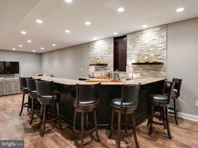 indoor wet bar featuring light wood-style flooring, recessed lighting, and baseboards