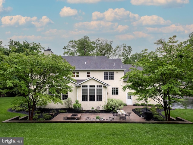 back of property featuring a patio area, a chimney, a lawn, and stucco siding