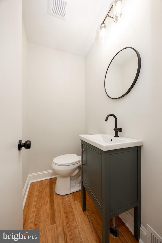 bathroom featuring vanity, toilet, wood finished floors, and baseboards