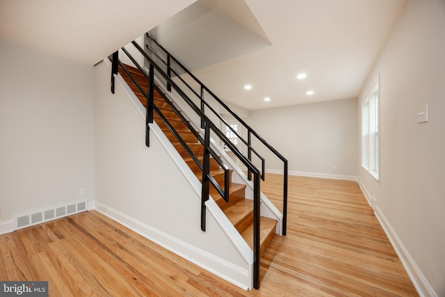 stairs with wood finished floors, recessed lighting, and baseboards