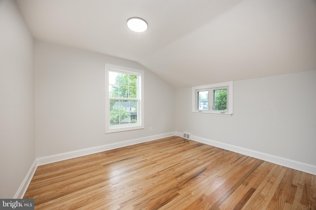 additional living space with light wood finished floors, plenty of natural light, baseboards, and lofted ceiling