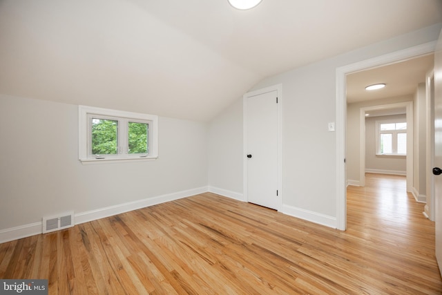 bonus room with light wood-style flooring, lofted ceiling, and baseboards