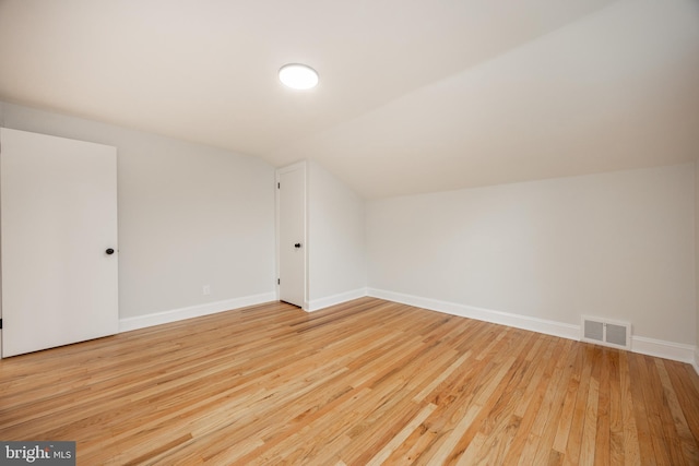 bonus room with vaulted ceiling, light wood finished floors, and baseboards