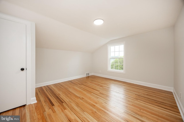 bonus room with vaulted ceiling, light wood finished floors, and baseboards