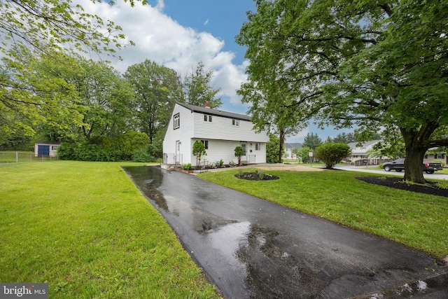 colonial house with driveway, a front yard, and a chimney
