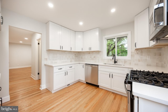 kitchen with stainless steel appliances, a sink, light wood finished floors, decorative backsplash, and recessed lighting