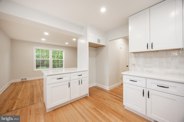kitchen with light wood-style floors, baseboards, backsplash, white cabinetry, and light countertops