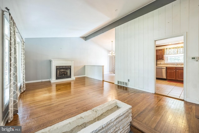 147 Heather Rd, Haddon Township, NJ 08107 - unfurnished living room featuring light wood-type flooring, a chandelier, a fireplace with raised hearth, and a sink