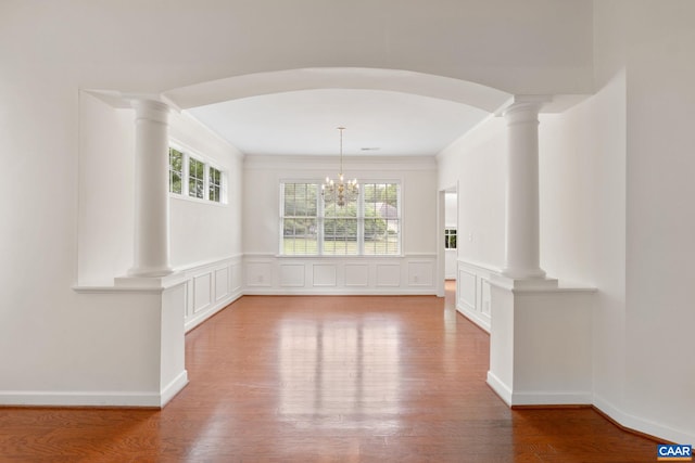 1269 Townbrook Xing, Charlottesville, VA 22901 - unfurnished dining area with arched walkways, wood finished floors, ornate columns, a chandelier, and wainscoting