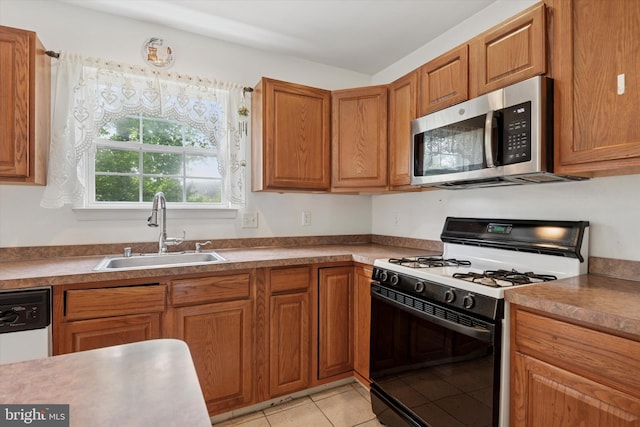 7 Gazelle Pl, New Castle, DE 19720 - kitchen with range with gas cooktop, stainless steel microwave, a sink, light tile patterned flooring, and brown cabinetry
