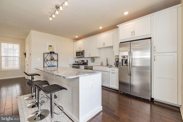 kitchen featuring appliances with stainless steel finishes, dark wood-type flooring, a sink, a kitchen island, and recessed lighting