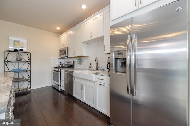 kitchen featuring appliances with stainless steel finishes, white cabinets, dark wood finished floors, light stone counters, and recessed lighting