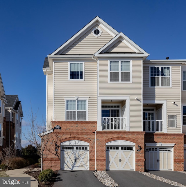 townhome / multi-family property featuring brick siding, driveway, and a garage